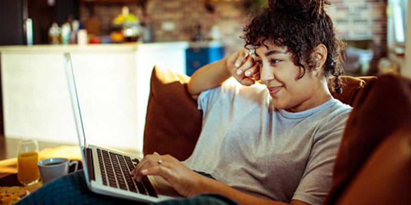 young latina on her computer while sitting on the couch in the living room 